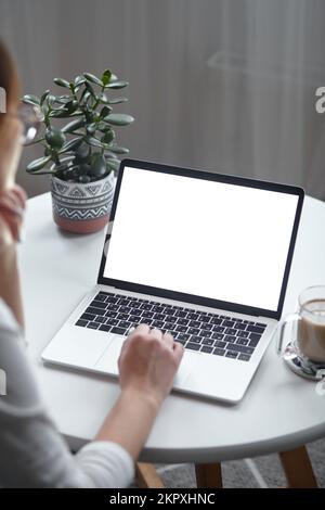 Mockup white screen laptop woman using computer while sitting at table at home, back view Stock Photo