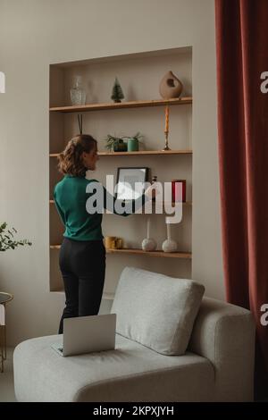 Young woman decorating the living room with Christmas decorations Stock Photo