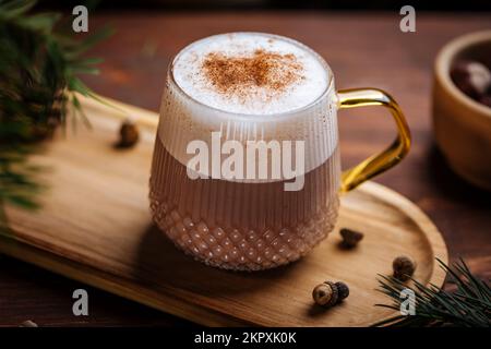 Glass mug of pumpkin spice late or eggnog in a festive, cozy and winter Christmas atmosphere. Home feeling mood. Stock Photo