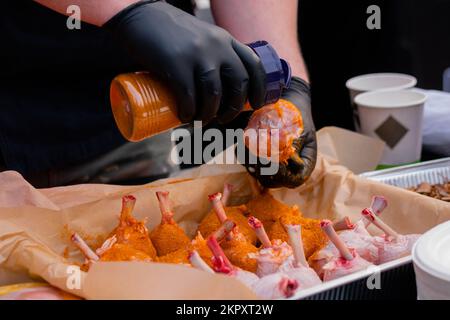 Chef preparing chicken legs with spices at street food festival - close up view Stock Photo