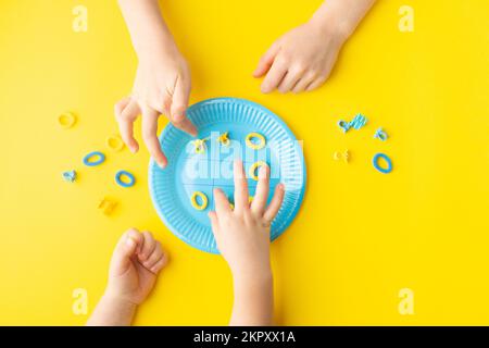 Playing noughts and crosses with hairpins on paper plate. Colorful concept. Minimalist concept. Stock Photo