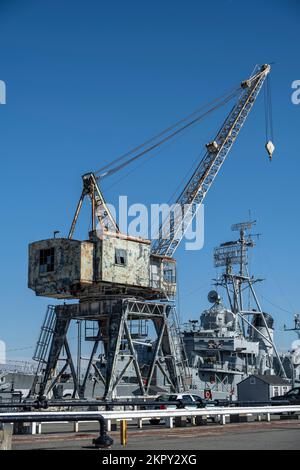 old crane at the Charlestown Navy Yard with the USS Cassin Young in the background Stock Photo