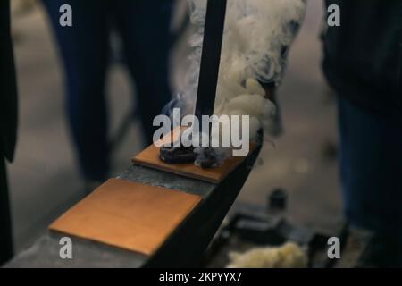 Kansas City Chiefs officials brand a piece of leather during their visit on Fort Riley, Kansas, Nov. 4, 2022. In 1853, the United States military started branding their horses on the left shoulder with the 'US' mark showing the horses belonged to the United States government. Stock Photo