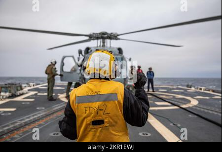 EASTERN ATLANTIC OCEAN (Nov. 5, 2022) Boatswain’s Mate 3rd Class Aaliyah Malcolm signals to the pilots in a MH-60R Seahawk helicopter, attached to the Helicopter Maritime Strike Squadron (HSM) 79, on the flight deck of the Arleigh Burke-class guided-missile destroyer USS Roosevelt (DDG 80), Nov. 5, 2022. Roosevelt is on a scheduled deployment in the U.S. Naval Forces Europe area of operations, employed by U.S. Sixth Fleet to defend U.S., allied and partner interests. Stock Photo