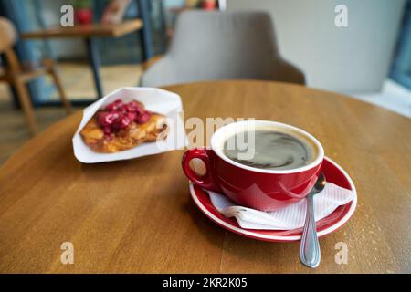 Cup of hot coffee and dessert with respberries served in cafe. Stock Photo