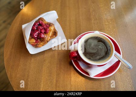 Cup of hot coffee and dessert with respberries served in cafe. Stock Photo