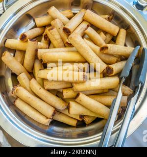 Looking down at spring rolls in a metal bowl at a buffet. Stock Photo
