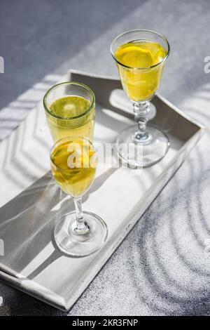 Three glasses of Limoncello with fresh lemon on a tray Stock Photo