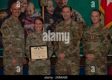 U.S. Army Chief Warrant Officer 2 Toni Serra (middle left) receivies a Military Outstanding Volunteer Service Medal from Maj. Gen. John Meyer III (left), commanding general of the 1st Infantry Division and Fort Riley, and Command Sgt. Maj. Christopher Mullinax (right), the command sergeant major of the 1st Inf. Div. and Fort Riley, Nov. 7, 2022, at Victory Hall in Fort Riley, Kansas. Serra received the award for her work as a volunteer in numerous positions within her brigade. Stock Photo