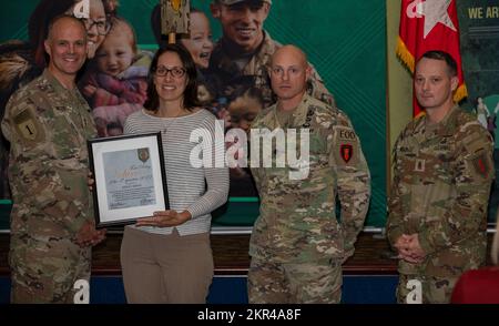 Ashley Jarvis (middle left) receives a Volunteer of the Quarter Award from Maj. Gen. John Meyer III (left), commanding general of the 1st Infantry Division and Fort Riley, and Command Sgt. Maj. Christopher Mullinax (right), the command sergeant major of the 1st Inf. Div. and Fort Riley, Nov. 7, 2022, at Victory Hall in Fort Riley, Kansas. Jarvis received the award for her work as a volunteer with the United Service Organization, Soldier Family Readiness Group and Cub Scout Pack 260. Stock Photo