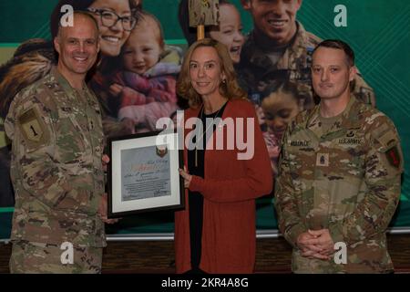 Tracey Phillips (middle) receives a Volunteer of the Quarter Award from Maj. Gen. John Meyer III (left), commanding general of the 1st Infantry Division and Fort Riley, and Command Sgt. Maj. Christopher Mullinax (right), the command sergeant major of the 1st Inf. Div. and Fort Riley, Nov. 7, 2022, at Victory Hall in Fort Riley, Kansas. Phillips received the award for her work in 3rd Battalion, 66th Armor Regiment's Soldier Family Readiness Group. Stock Photo