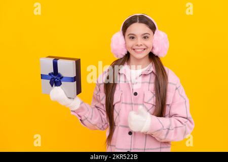 merry christmas. happy kid in winter earmuffs with box. teen girl in mittens Stock Photo