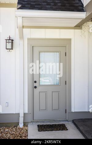 A taupe rear side back door of a new construction cream color house with hardy board siding near the patio entrance Stock Photo