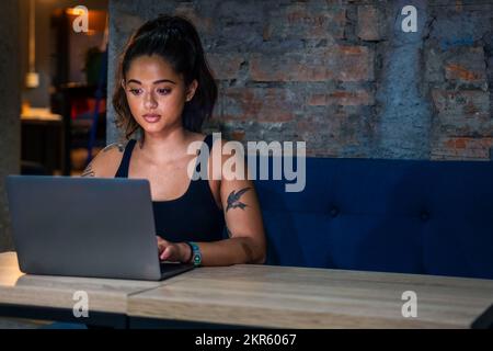 Female digital nomad working on laptop in contemporary coworking space Stock Photo