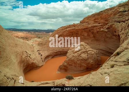 Hikers visit a unique sandstone geological feature known as the 'Cosmic Ashtray' located in Grand Staircase-Escalante National Monument in Utah Stock Photo