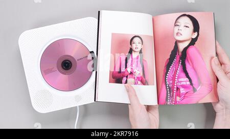 Fan hands holding BlackPink BORN PINK 2nd Album photobook with Jennie on grey. Pink music CD in player. South Korean girl group BlackPink. Space for t Stock Photo