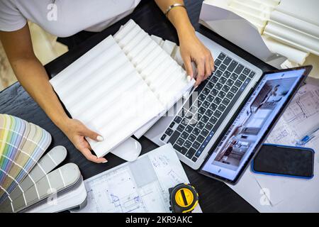 Khabarovsk, Russia, Desember 16, 2021. Closeup female interior designer hands choosing furniture material and color samples working studio Stock Photo