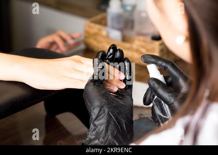 The manicure master treats the client's nails with antiseptic. Beauty salon. Stock Photo