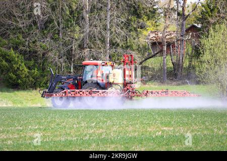 Farmer spraying field with Valtra tractor and Hardi Master Plus liftmounted sprayer on a day of spring. Salo, Finland. May 16, 2021. Stock Photo