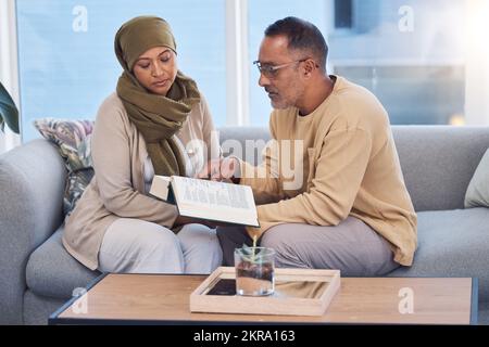 Muslim couple, bonding and reading book, holy koran or traditional prayer quran on sofa in house or home living room. Islamic man, middle aged woman Stock Photo