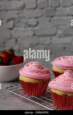 close up of vanilla muffins decorated with pink buttercream frosting on top Stock Photo