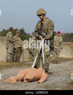 U.S Army Spc. James Palovich from the Headquarters and Headquarters Company, 63rd Theater Aviation Brigade, prepares to move a medical dummy as required in the stress shoot at the Kentucky National Guard's Best Warrior Competition at Wendell H. Ford Regional Training Center in Greenville, Ky., on Nov. 10, 2022. The competing Soldiers represent their units and brigades in an intense gauntlet to find out who will advance onto the Regional Best Warrior Competition. Stock Photo