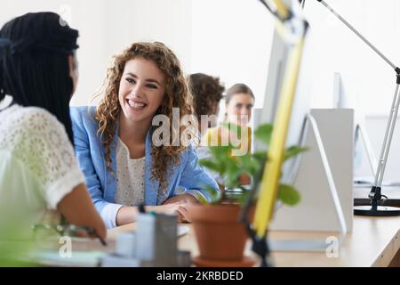 Sharing their creativity. young designers talking while working on their computers. Stock Photo