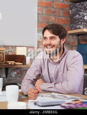 Feeling inspired. A handsome young designer smiling as he works in his office. Stock Photo