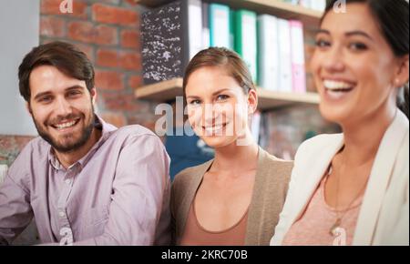Getting the job done with a smile. three business associates working together on a project. Stock Photo