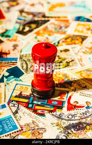 Icons of Great Britain with the red pillar postbox placed on a mix of United Kingdom stamps Stock Photo