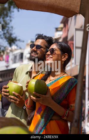 Portrait of young couple drinking green coconut water on street Stock Photo