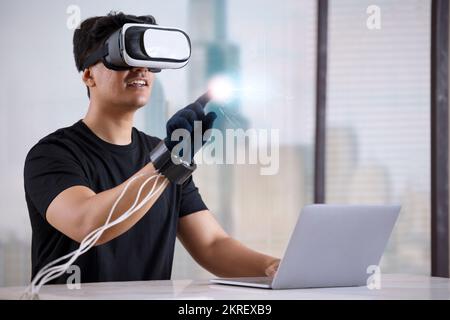 Man wearing VR headset and haptic glove interacting with virtual object/person in the metaverse Stock Photo