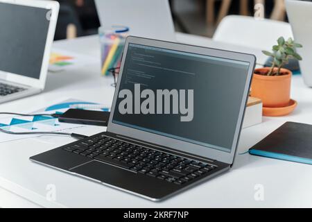 Close-up of laptop with codes on monitor on desk of programmer at IT office Stock Photo