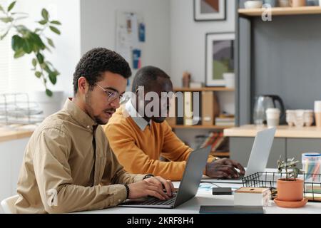 Young developers typing on computers at table, they working over new software at IT office Stock Photo