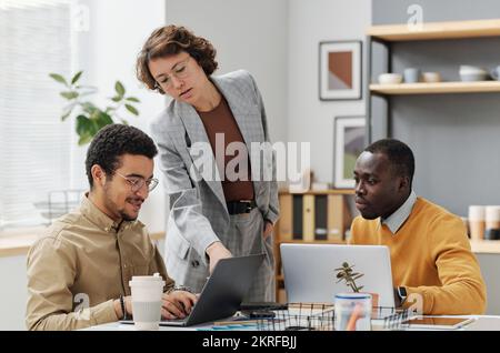 Young programmers working in team during meeting, they working on computers with new software Stock Photo
