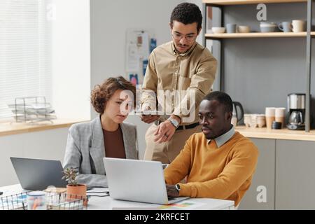 Young business team working over new computer program on laptop together during meeting at office Stock Photo