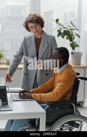 Young businesswoman discussing online presentation together with programmer with disability Stock Photo