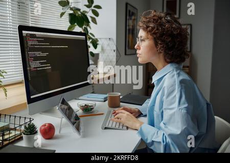 Serious young businesswoman concentrating on her online work on computer, she typing computer codes at her workplace Stock Photo