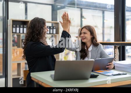 Two happy friendly diverse professionals, cheerful successful business partners colleagues giving high five celebrating business triumph in office Stock Photo