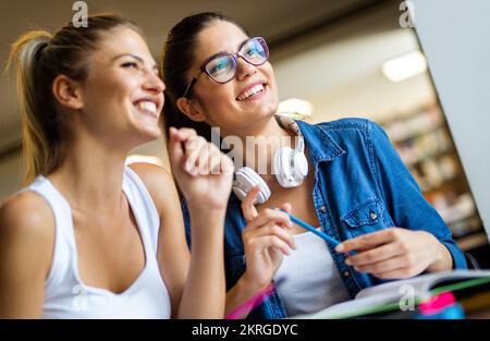 Happy young university students studying with books in library. Stock Photo