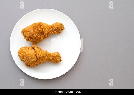 Two roasted fried chicken legs or chicken drumstick on a white ceramic plate, top view Stock Photo