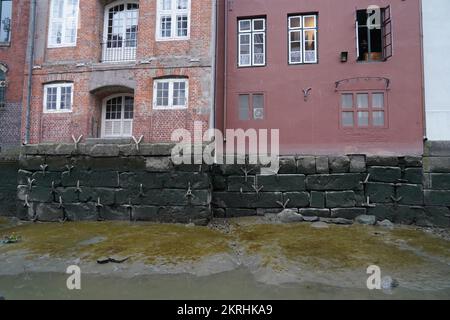 Old brick building painted pink situated in historical part of town Hamburg on the bank channel river Elbe during low tide. Stock Photo
