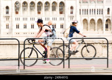 Man bicyclist carrying baby on the back in the city Stock Photo