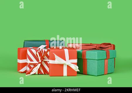 Various small Christmas gift boxes on green background with copy space Stock Photo