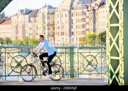 Man riding bicycle on the bridge against old houses block Stock Photo