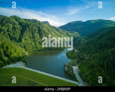 Small intermountain lake bay with highway on shore and high peaks of Rhodope Mountains surrounded by sheltered forests Stock Photo