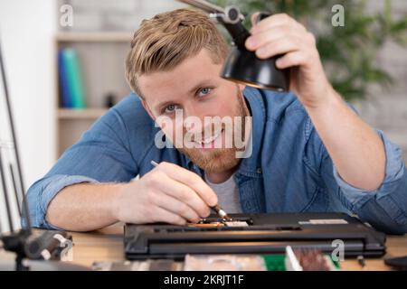 young technician working on broken computer in his office Stock Photo
