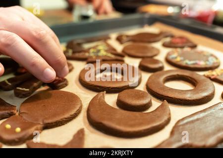 Close-up of a man's hand decorates a festive gingerbread cookie before baking Stock Photo