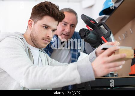 student and teacher in carpentry class using circular saw Stock Photo