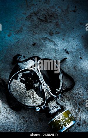 Dark blue photo of a nighttime vintage gas mask lying on sand. Cold war casualties Stock Photo